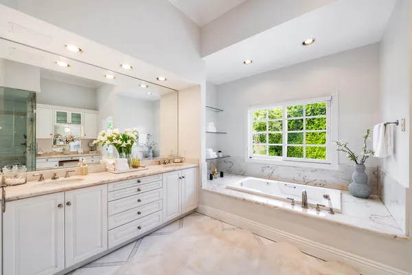 a bathroom with a double vanity sink large mirror and a bathtub