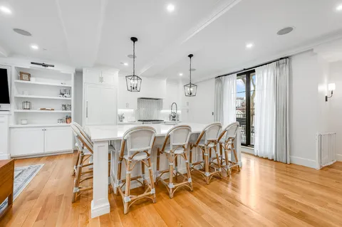a kitchen with stainless steel appliances kitchen island granite countertop a table chairs and a wooden floor