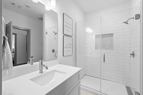 a bathroom with a sink shower and a mirror