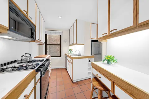 a kitchen with stainless steel appliances a stove a sink cabinets and a window
