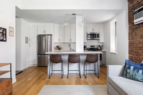 a living room with stainless steel appliances kitchen island granite countertop furniture and a wooden floor