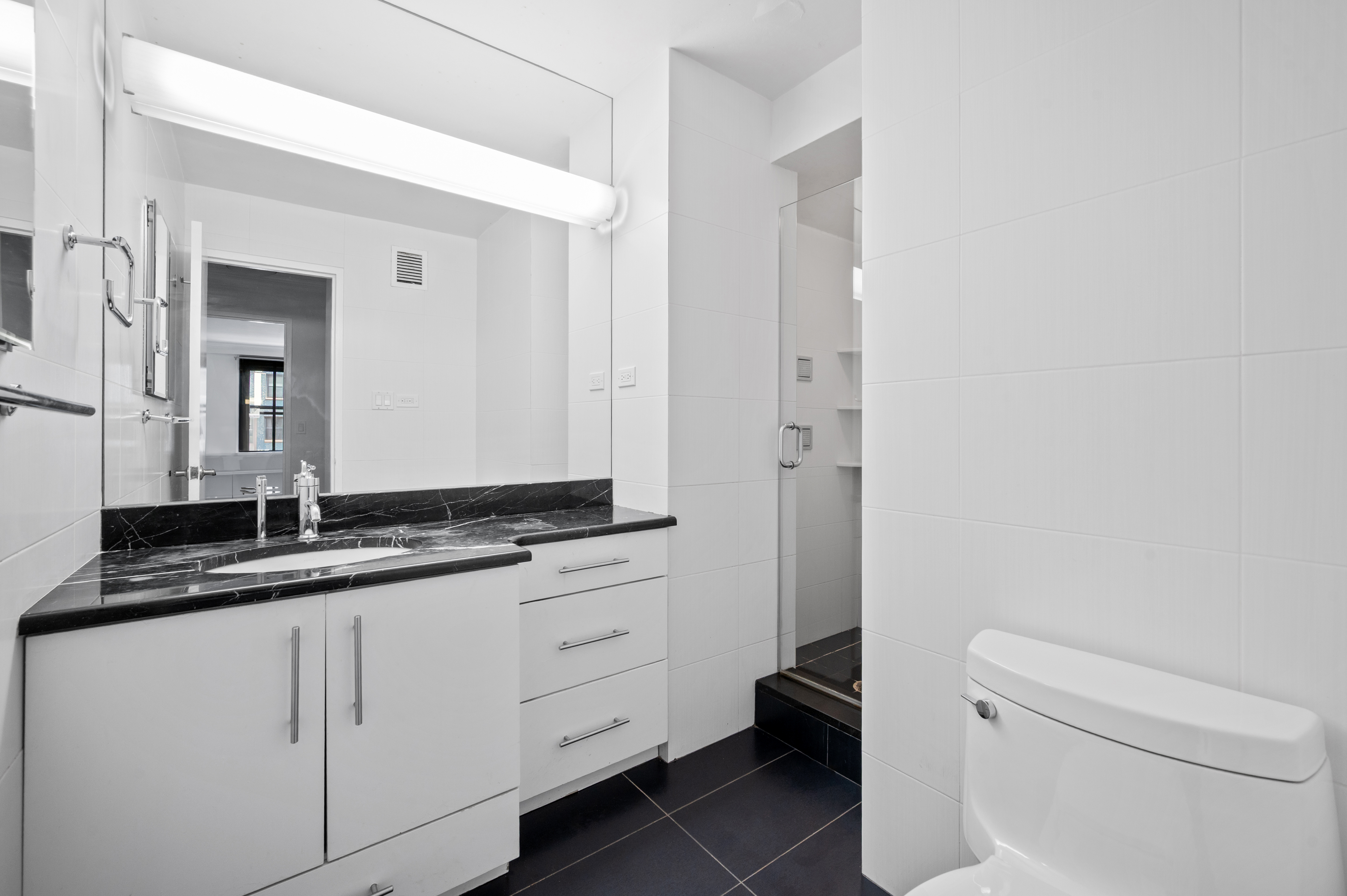 225 East 57th Street, Unit 14F Manhattan, NY 10022 - Photo 13 of 14 a bathroom with a granite countertop sink a toilet and a mirror