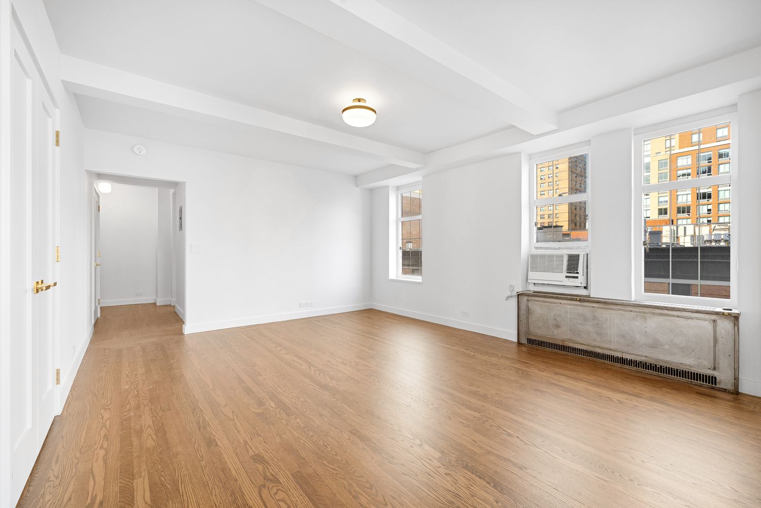 a view of an empty room with wooden floor and a window