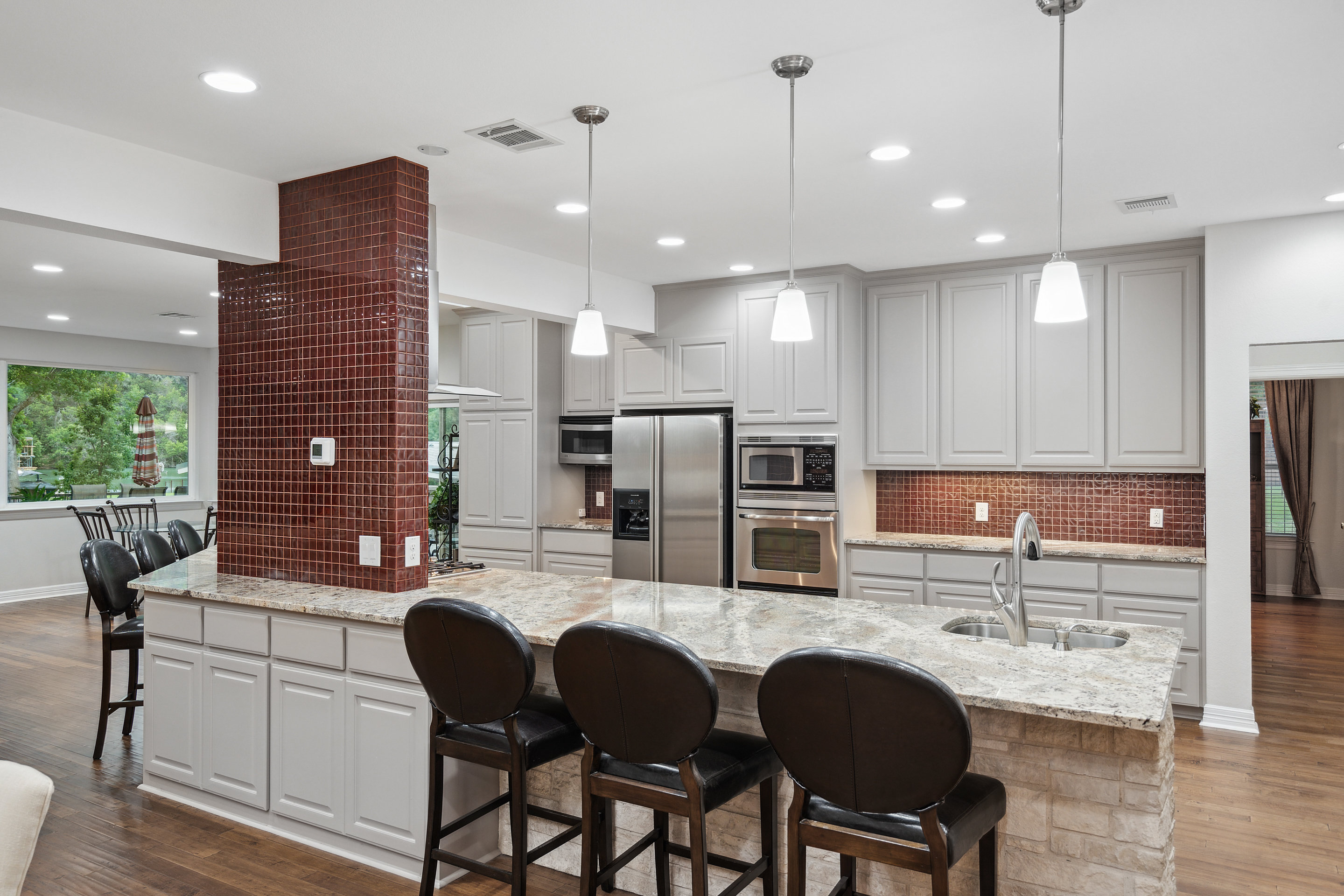 2603 Pearce Road Austin, TX 78730 - Photo 12 of 41 a kitchen with stainless steel appliances granite countertop sink wooden cabinets dining table and chairs