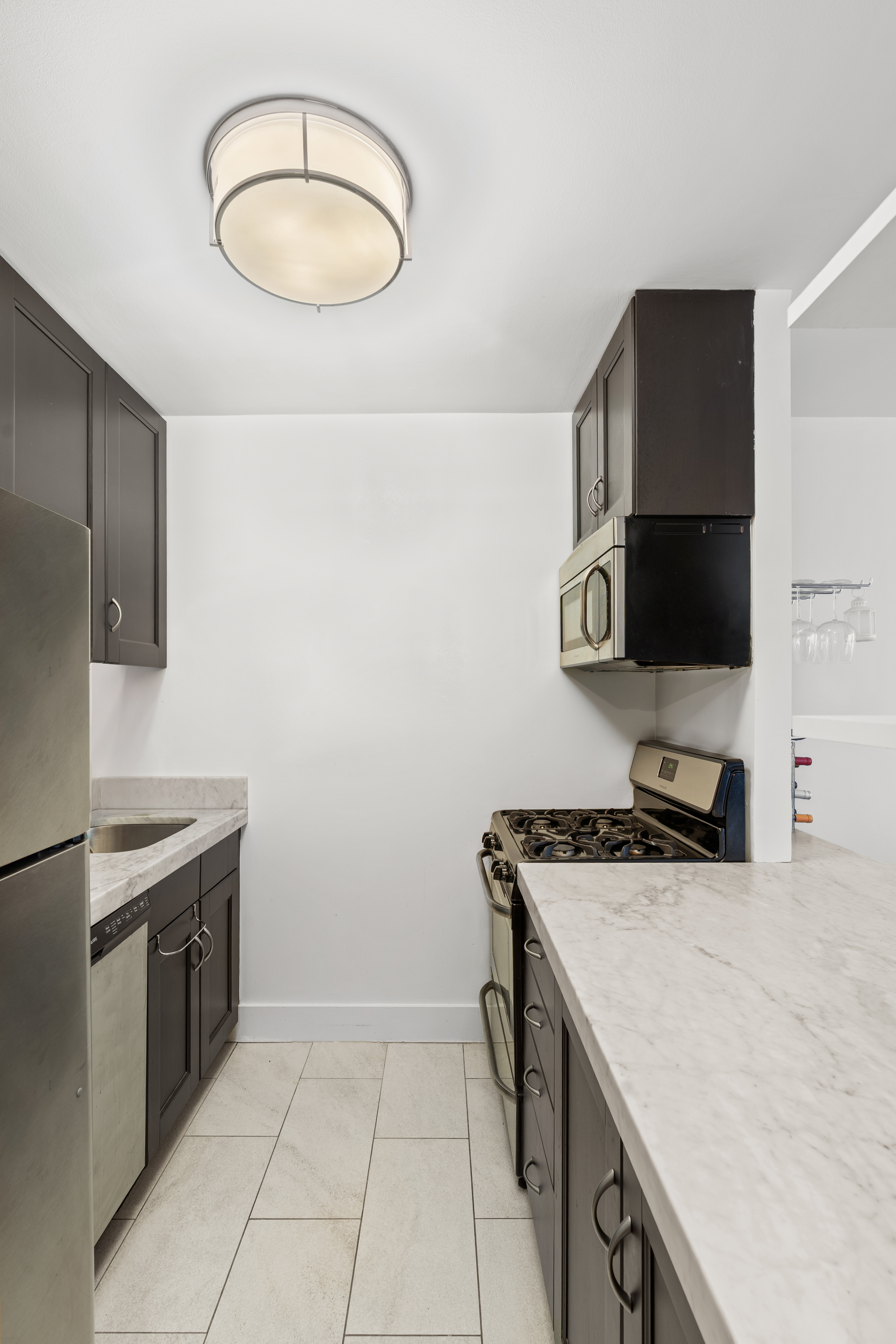 330 East 75th Street, Unit 4K Manhattan, NY 10021 - Photo 5 of 9 a kitchen with stainless steel appliances a stove microwave and sink