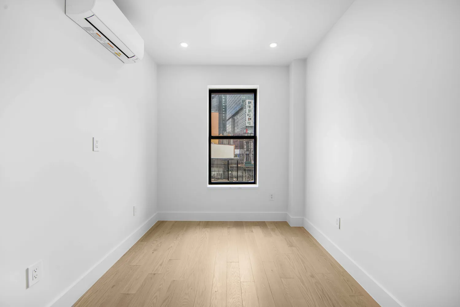 an empty room with a window and wooden floor