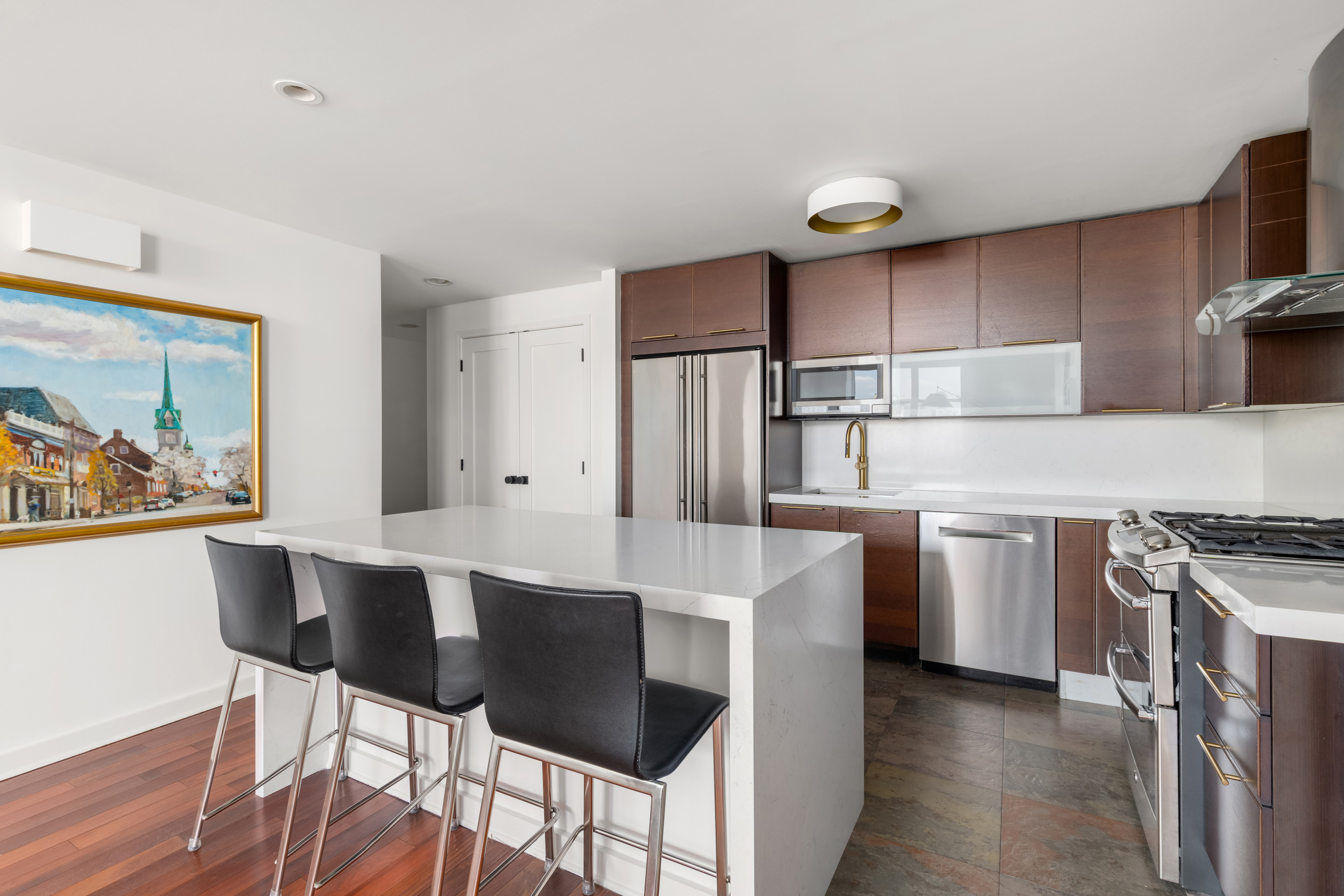 301 West 118th Street, Unit PH1C Manhattan, NY 10026 - Photo 3 of 12 a kitchen with stainless steel appliances a stove a refrigerator and a dining table with wooden floors