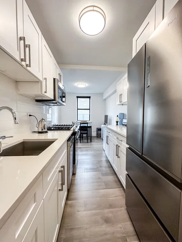 a large white kitchen with stainless steel appliances lots of counter space and wooden floor