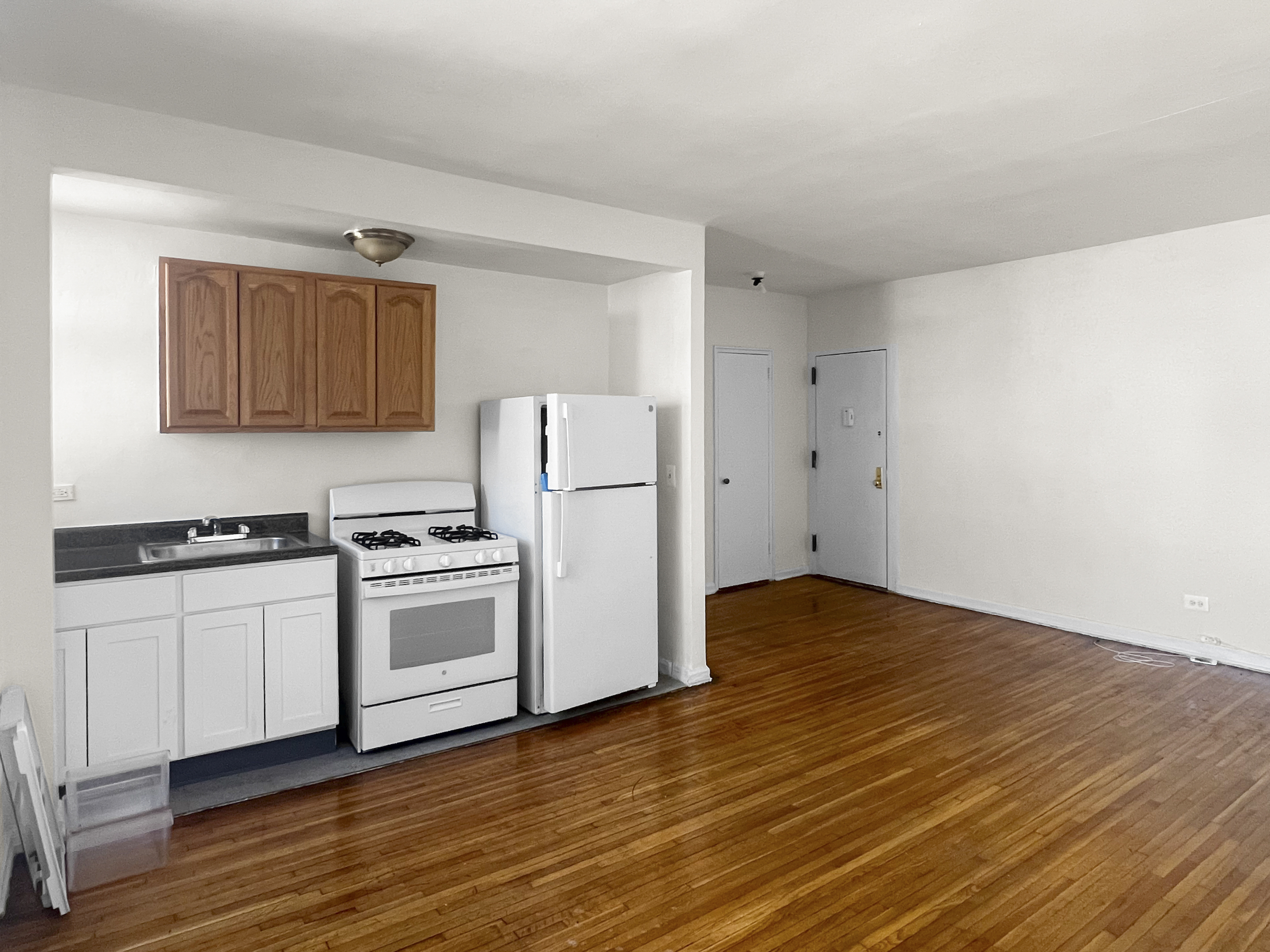 1466 East Gun Hill Road, Unit 1B Bronx, NY 10469 - Photo 2 of 5 a kitchen with granite countertop a stove a refrigerator and a stove with wooden floors