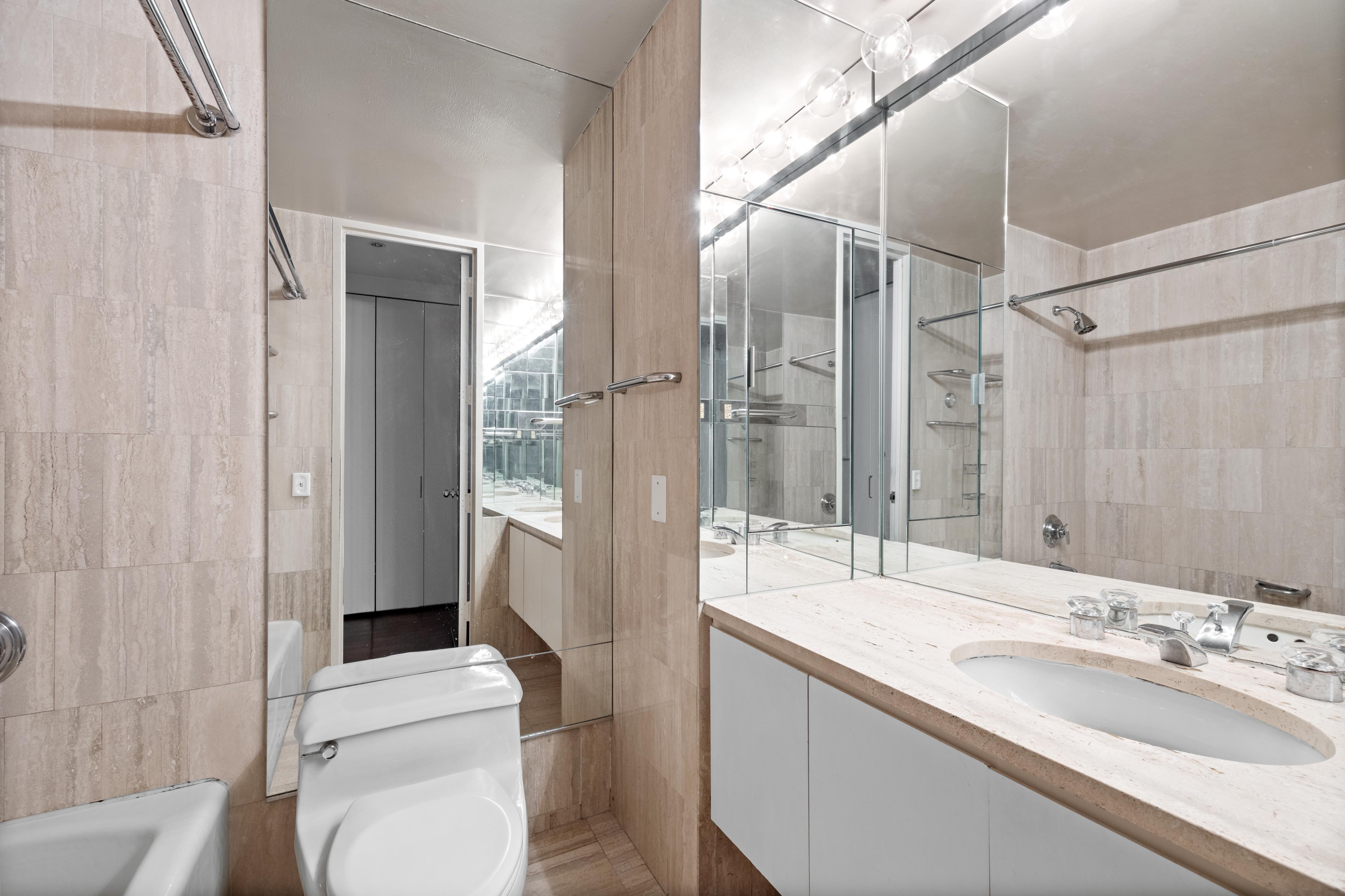 15 West 53rd Street, Unit 10H Manhattan, NY 10019 - Photo 7 of 11 a bathroom with a sink a toilet and shower