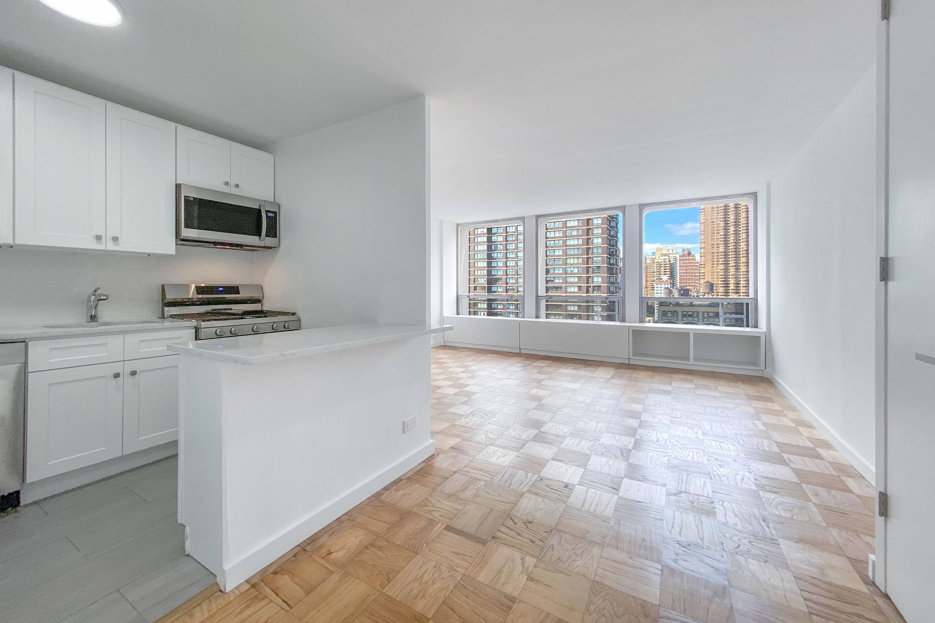 300 East 33rd Street, Unit 18F Manhattan, NY 10016 - Photo 1 of 15 a kitchen with granite countertop a stove a sink and a white cabinets