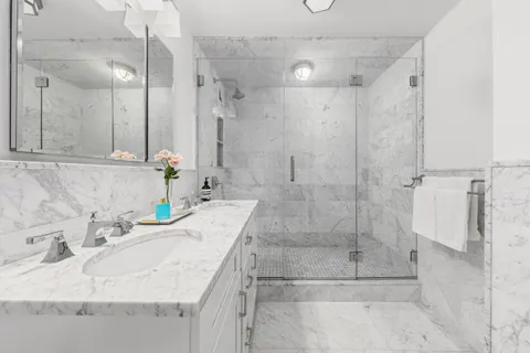 a bathroom with a granite countertop shower a sink and a mirror
