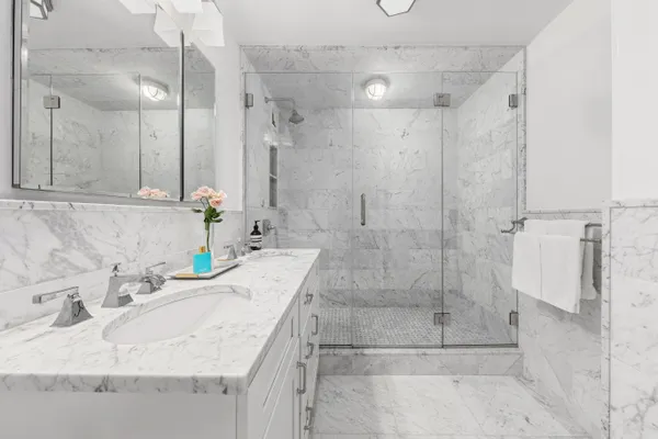 a bathroom with a granite countertop shower a sink and a mirror