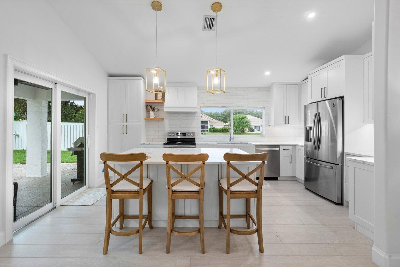 1182 Canoe Point Delray Beach, FL 33444 - Photo 10 of 46 a kitchen with stainless steel appliances kitchen island granite countertop a refrigerator and a stove top oven