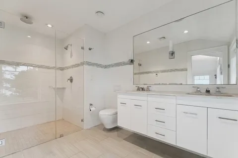 a bathroom with a granite countertop sink mirror and toilet