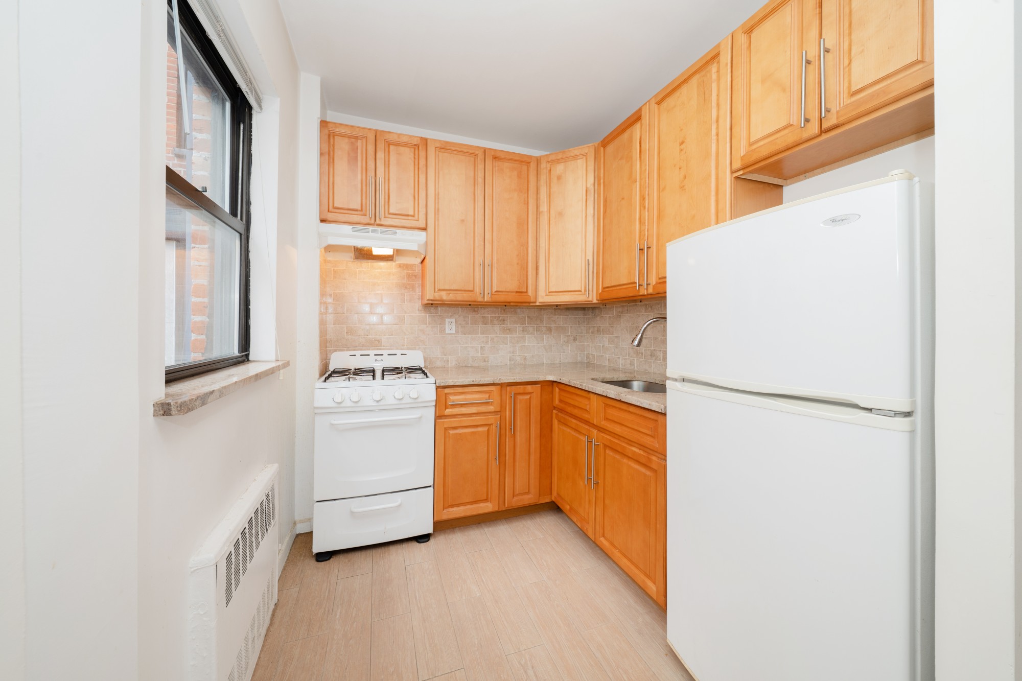 99-52 66th Road, Unit 1H Queens, NY 11374 - Photo 5 of 11 a kitchen with a refrigerator sink and cabinets