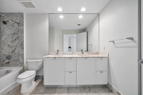 a bathroom with a granite countertop sink a toilet and shower