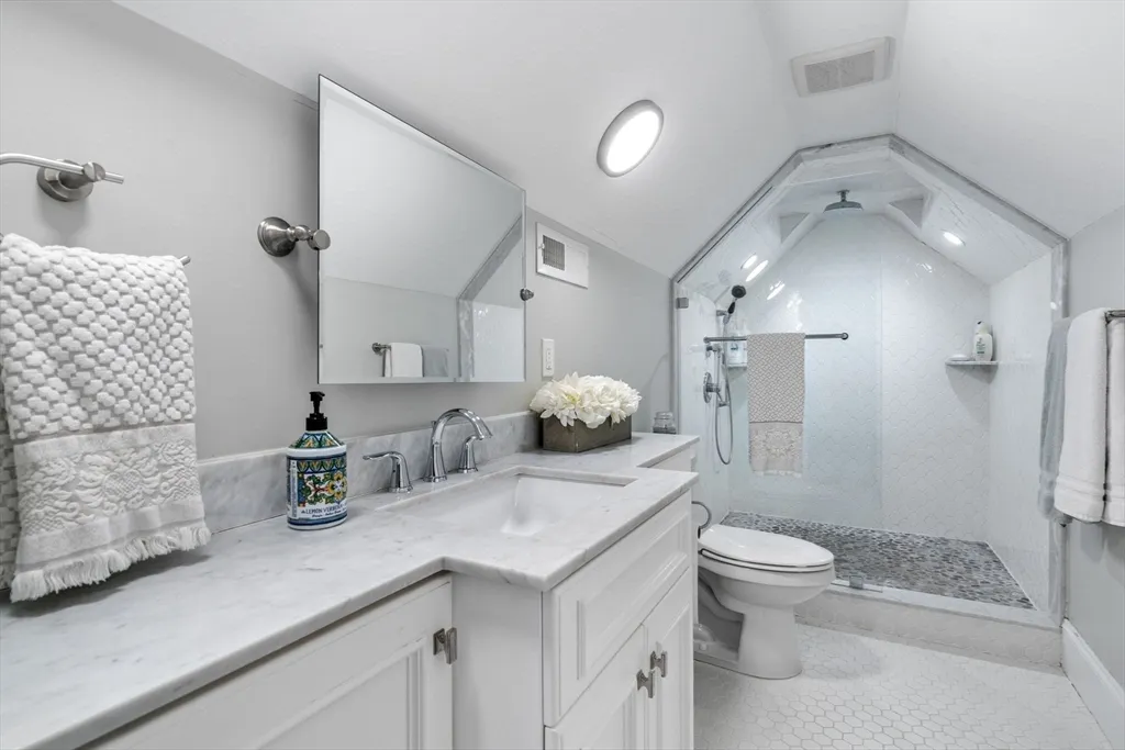 a bathroom with a granite countertop sink mirror vanity and next to a window