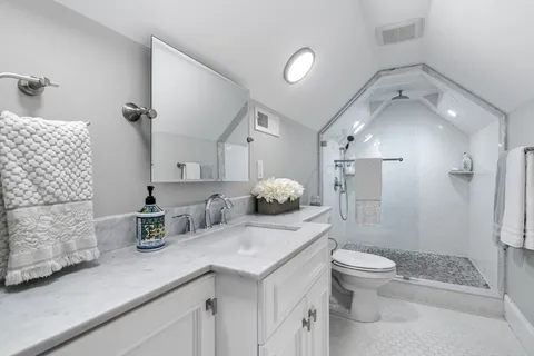 a bathroom with a granite countertop sink mirror vanity and next to a window