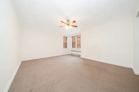 an empty room with a window and a ceiling fan