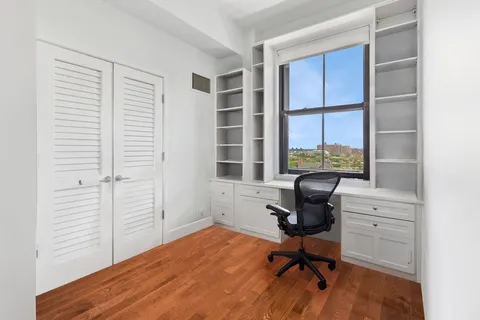 a view of a workspace with furniture and a window