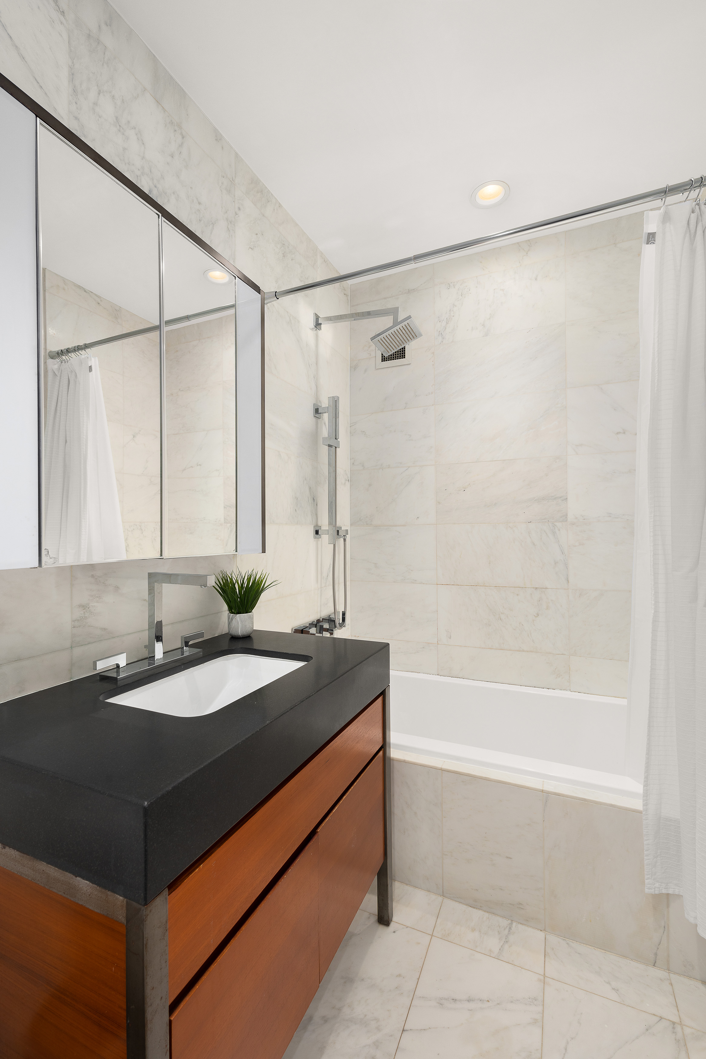 75 Wall Street, Unit 33L Manhattan, NY 10005 - Photo 5 of 5 a bathroom with a granite countertop sink a mirror and a bathtub