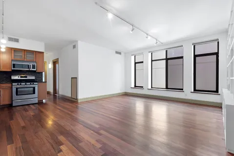 an empty room with wooden floor closet and windows