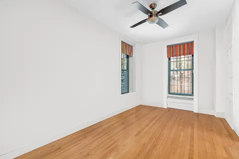 a view of empty room with wooden floor and fan