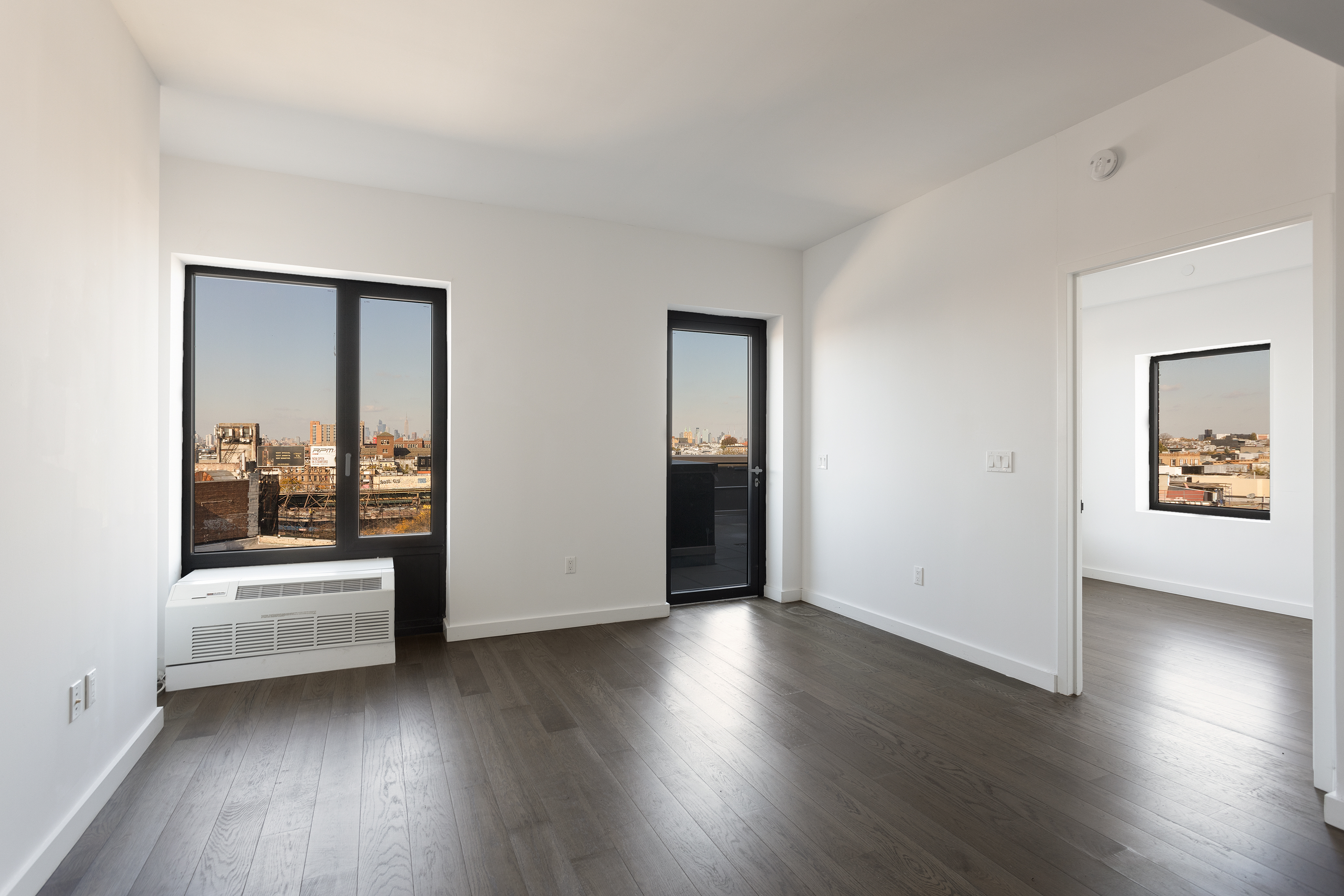 16-26 Madison Street, Unit PHA Queens, NY 11385 - Photo 7 of 16 an empty room with wooden floor and windows