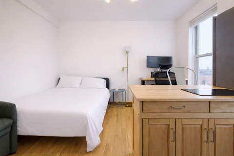 a bedroom with a bed and a flat tv screen on the dresser