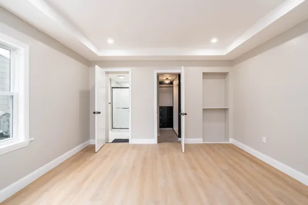 a view of empty room with wooden floor and window