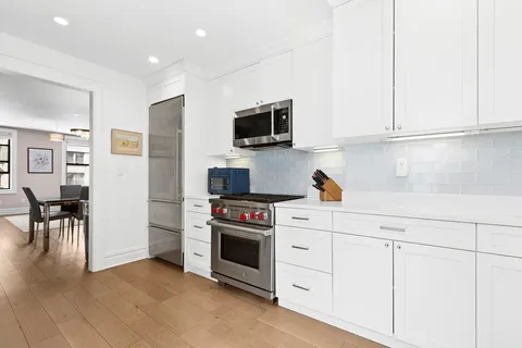 a kitchen with white cabinets and stainless steel appliances
