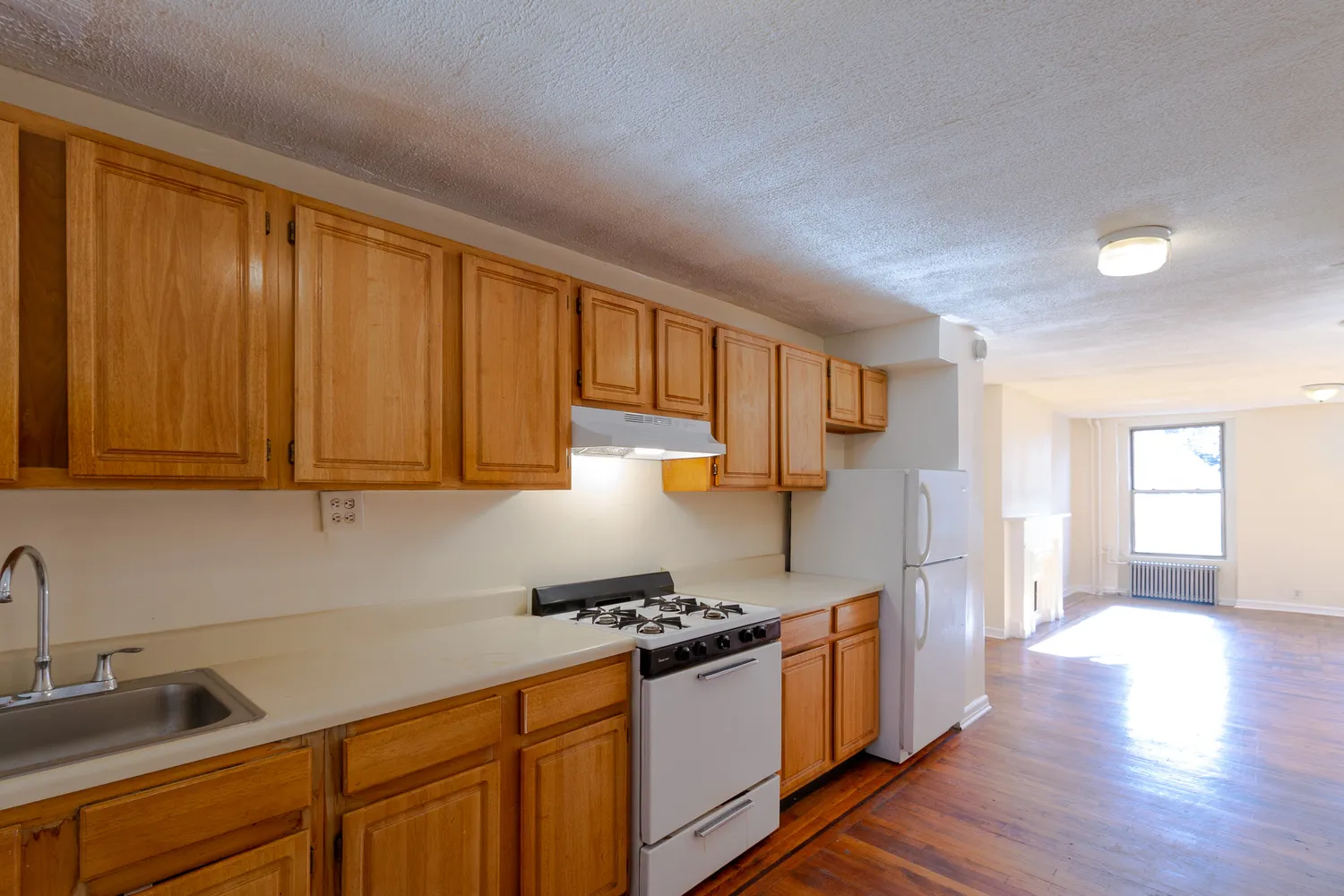 a kitchen with stainless steel appliances granite countertop a refrigerator a sink dishwasher and wooden cabinets with wooden floor