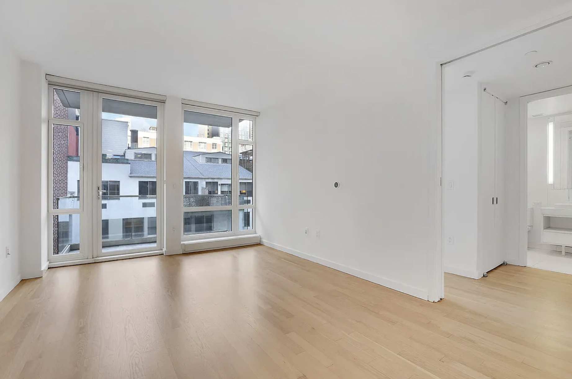 133 West 22nd Street, Unit 7H Manhattan, NY 10011 - Photo 3 of 22 a view of an empty room with wooden floor and a window