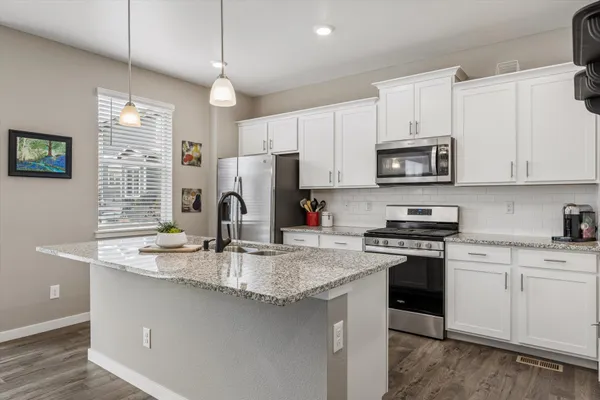 a kitchen with kitchen island granite countertop a stove sink microwave and refrigerator