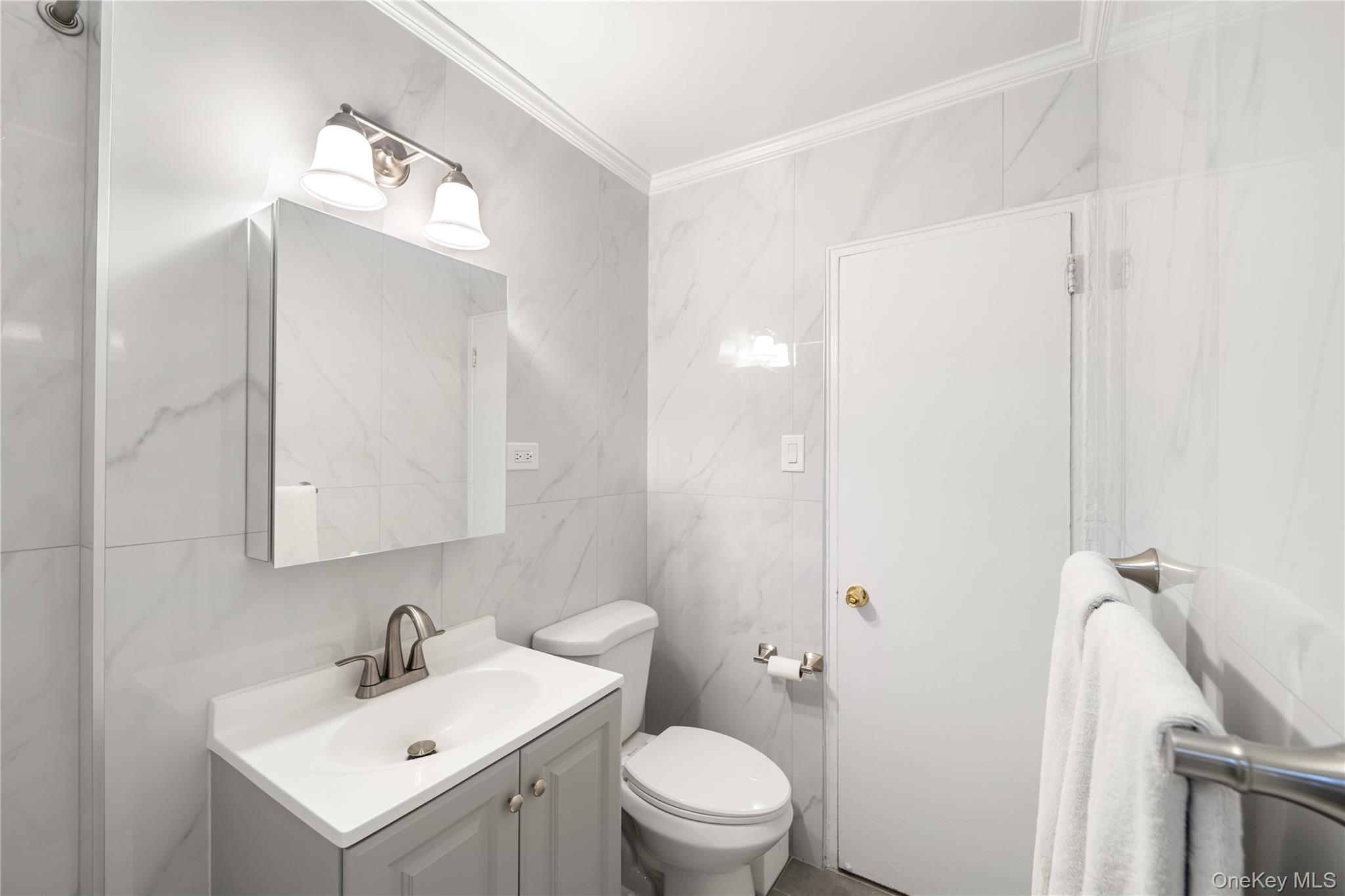217-14 73rd Avenue, Unit 1 Queens, NY 11364 - Photo 12 of 19 a bathroom with a toilet a sink a mirror and vanity