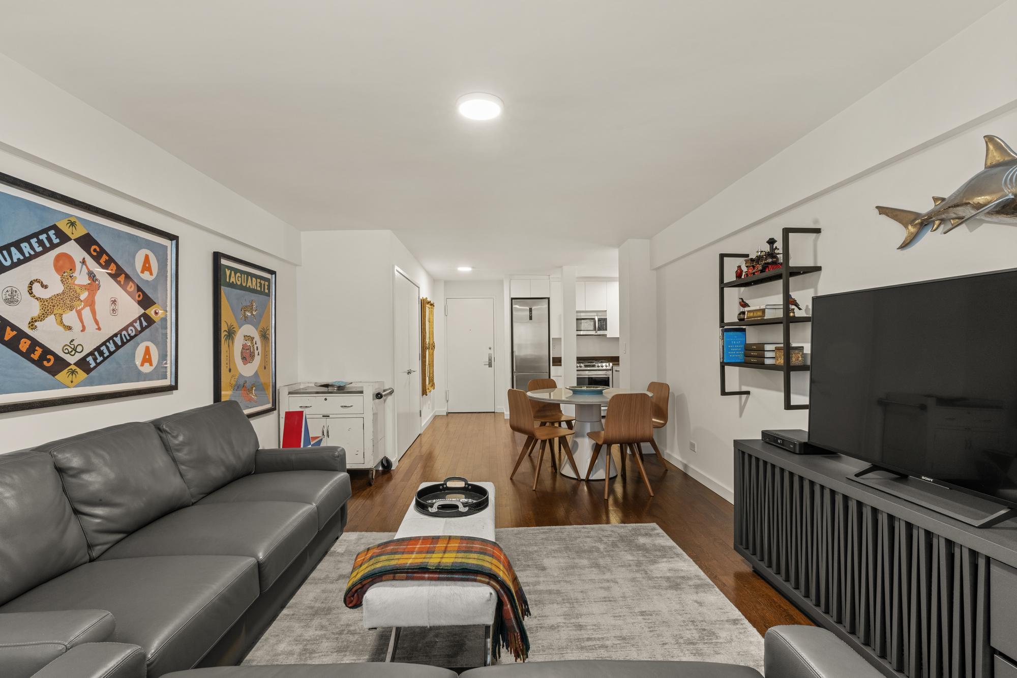 425 East 63rd Street, Unit W6A Manhattan, NY 10065 - Photo 2 of 11 a living room with furniture a rug and a flat screen tv