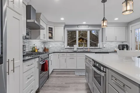a kitchen with stainless steel appliances granite countertop a sink stove and cabinets