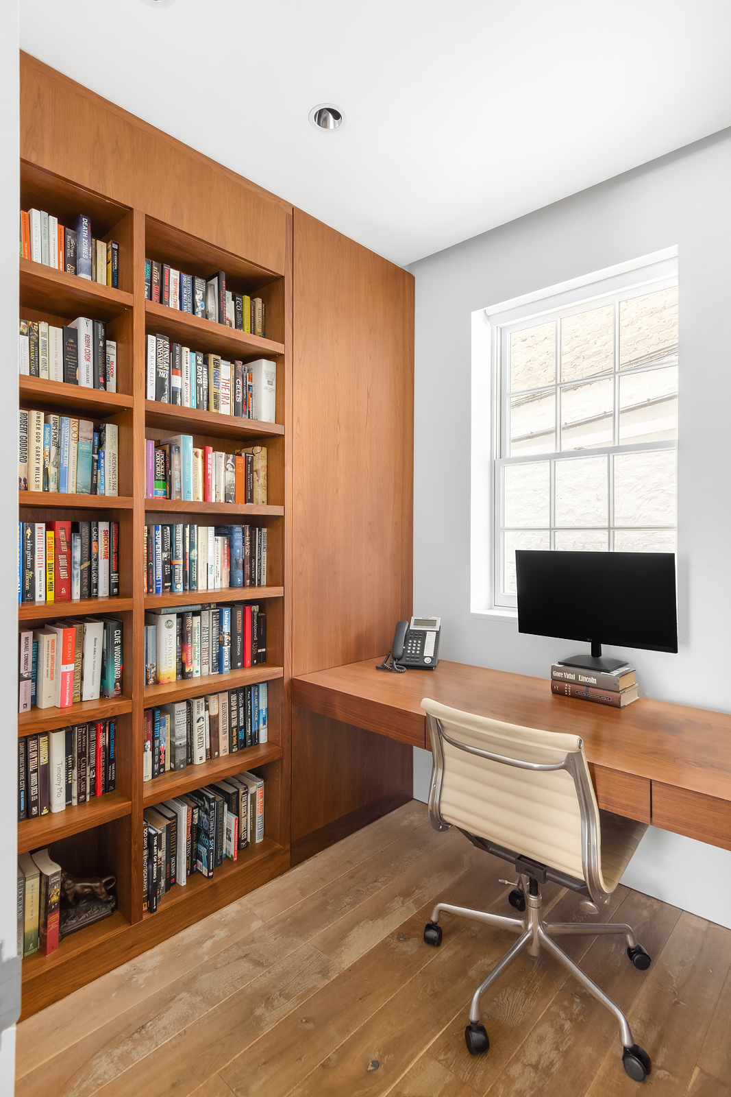 130 Charles Street Manhattan, NY 10014 - Photo 4 of 14 a view of a workspace with a bookshelf and a window