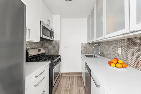 a kitchen with granite countertop a sink a stove and cabinets