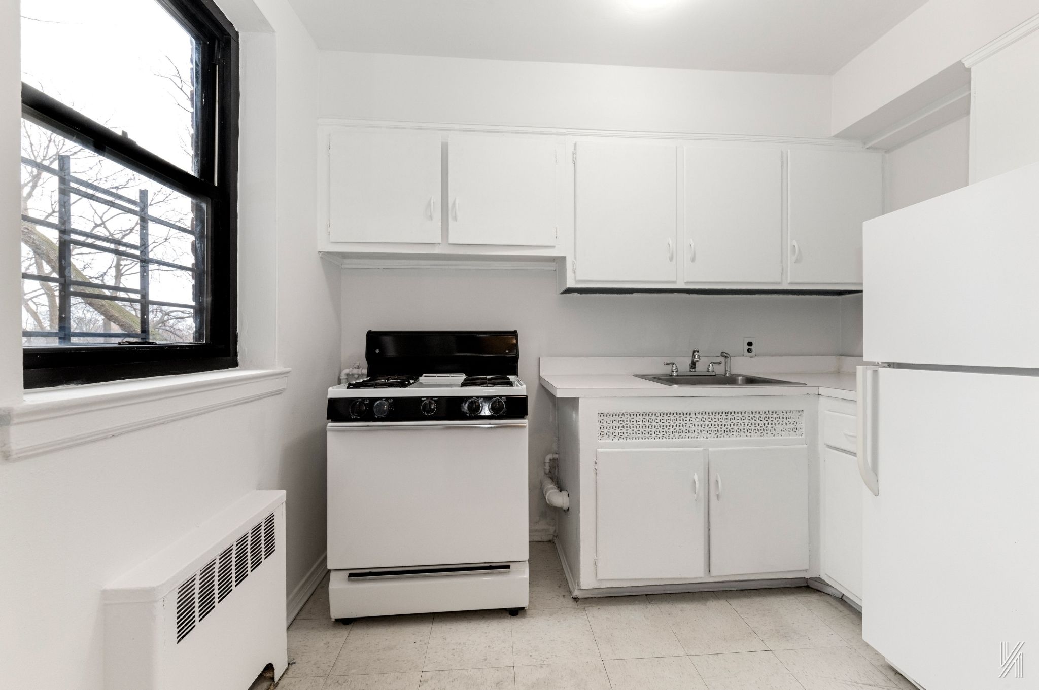 22-60 79th Street, Unit 3E Queens, NY 11370 - Photo 14 of 17 a kitchen with white cabinets and white appliances