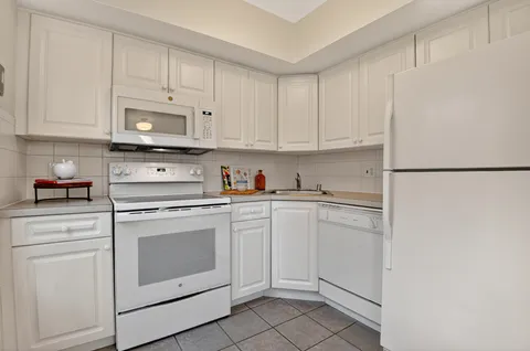 a kitchen with white cabinets and white appliances