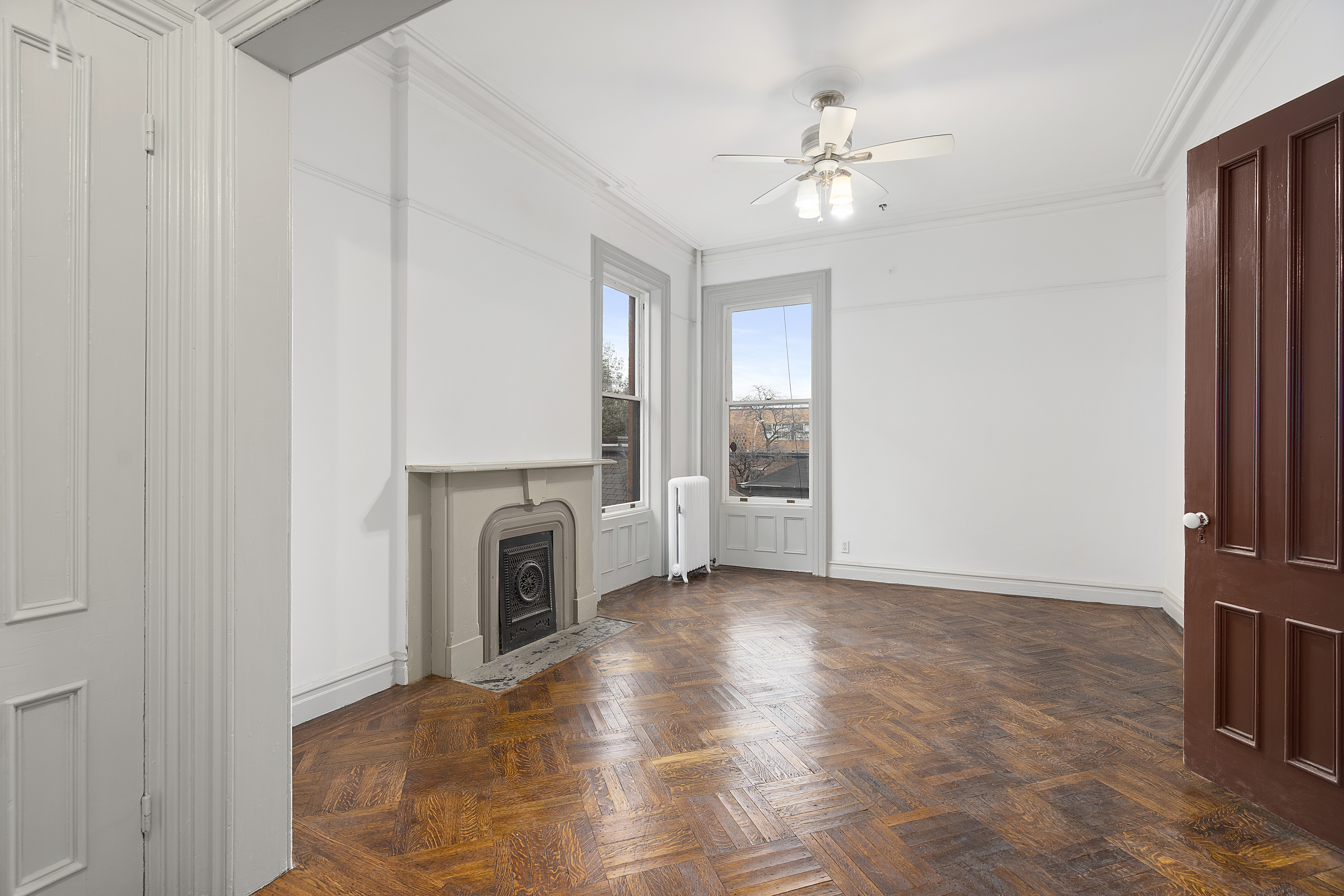 419 Clinton Avenue Brooklyn, NY 11238 - Photo 14 of 19 a view of a livingroom with a fireplace a ceiling fan and windows