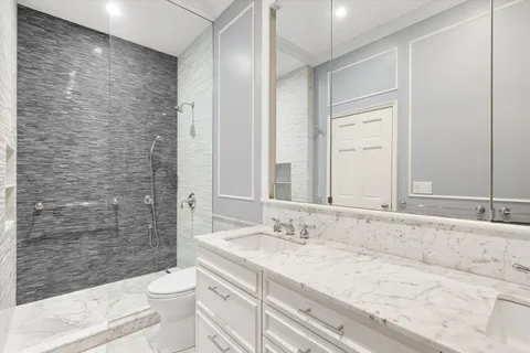 a bathroom with a granite countertop sink a toilet and shower