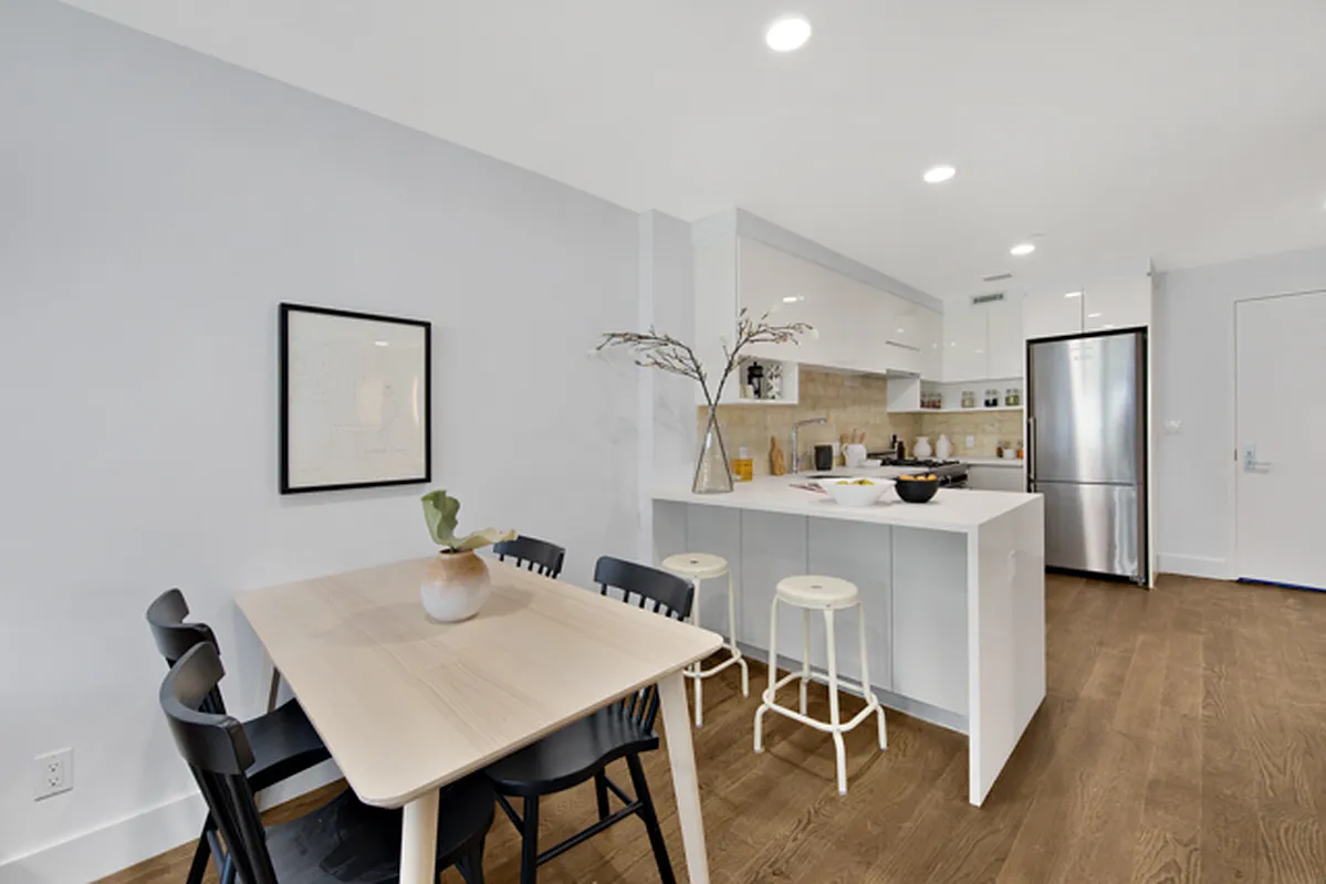 863 Saint Marks Avenue, Unit 4A Brooklyn, NY 11213 - Photo 2 of 6 a kitchen with stainless steel appliances granite countertop a dining table chairs refrigerator and cabinets