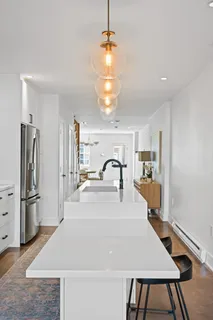 a view of a kitchen with kitchen island a stove a refrigerator and a view of living area