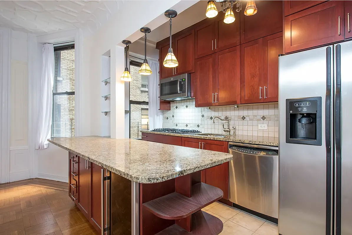 200 West 54th Street, Unit 6C Manhattan, NY 10019 - Photo 3 of 5 a kitchen with stainless steel appliances granite countertop table chairs sink and refrigerator