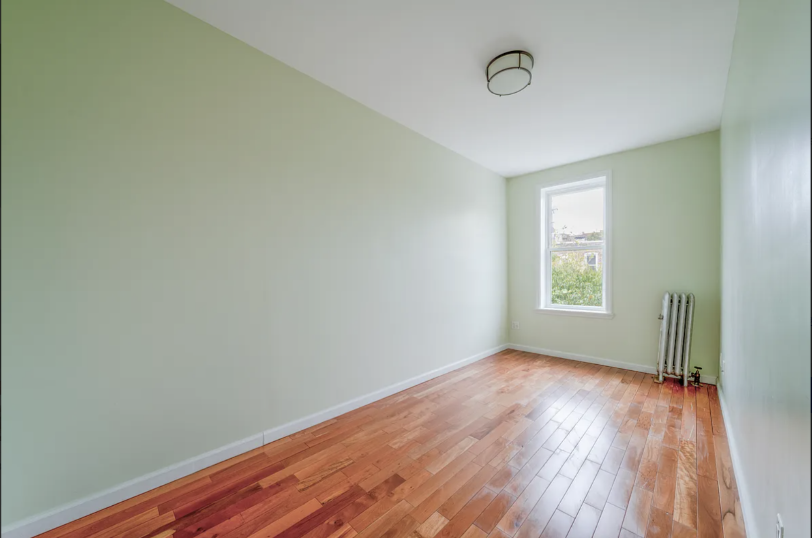 96 East 32nd Street, Unit 2 Brooklyn, NY 11226 - Photo 4 of 6 an empty room with wooden floor and windows
