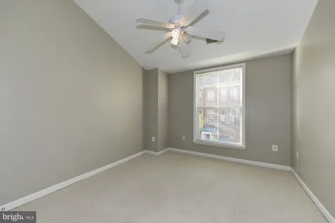 an empty room with windows and ceiling fan