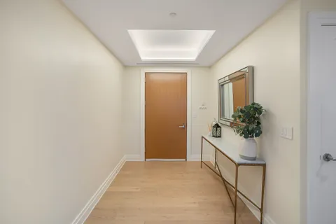 a view of a hallway with wooden floor and paintings on the wall
